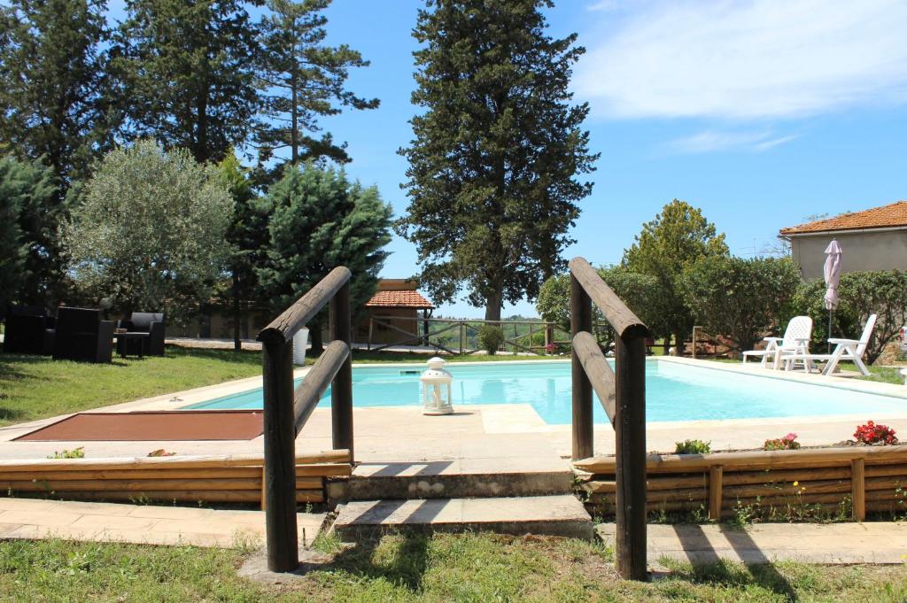 a swimming pool with two wooden railings next to it at Casa vacanza Podere Ristoro in San Giovanni dʼAsso