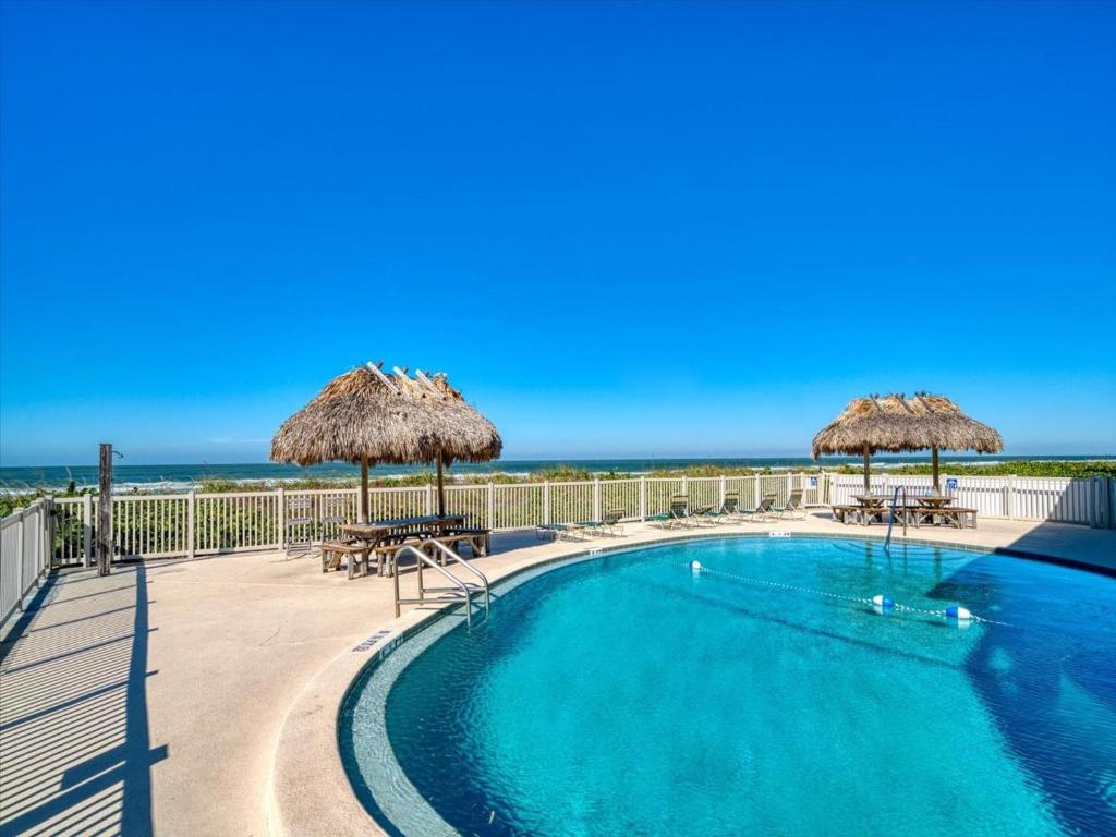 a swimming pool with umbrellas and the ocean in the background at Chateau 6W Alluring Beachfront Condo in Clearwater Beach