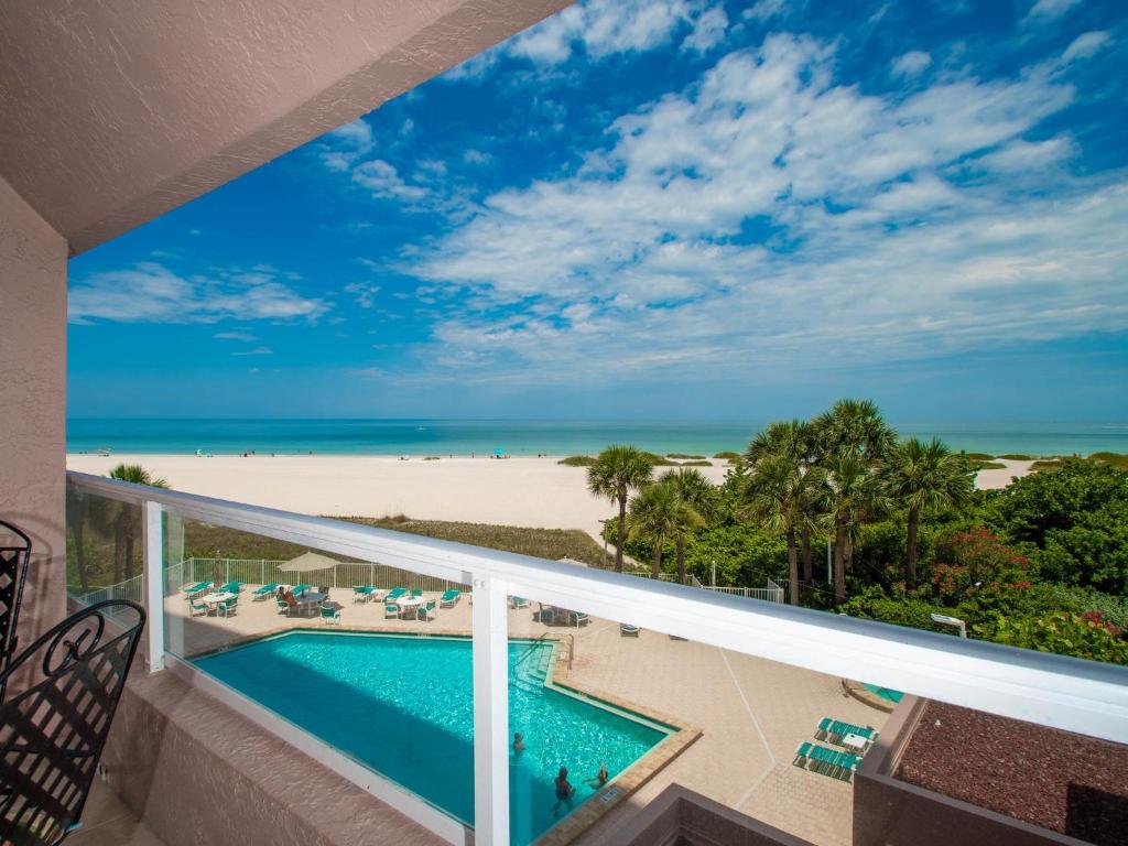 a balcony with a view of a beach and a swimming pool at Crescent Beach Club 3B Beachfront Views of the Gulf in Clearwater Beach