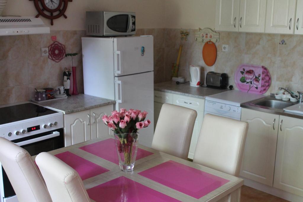a kitchen with a table with a vase of flowers on it at Emerald Suite in Valjevo