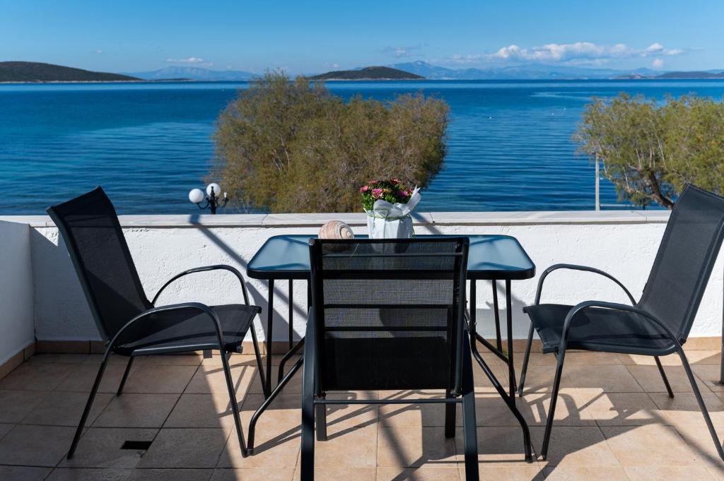 einen Tisch und Stühle auf einem Balkon mit Blick auf das Wasser in der Unterkunft O Molos in Marmarion