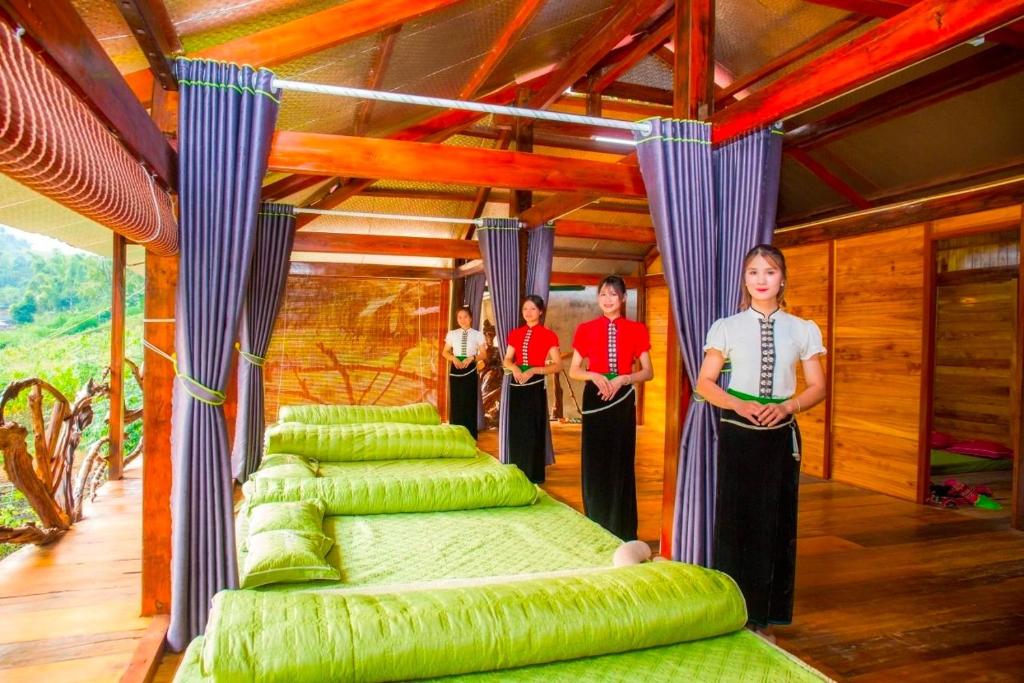 a group of people standing in a room with green beds at Homestay Toan Tra Tram Tau in Cham Ta Lao