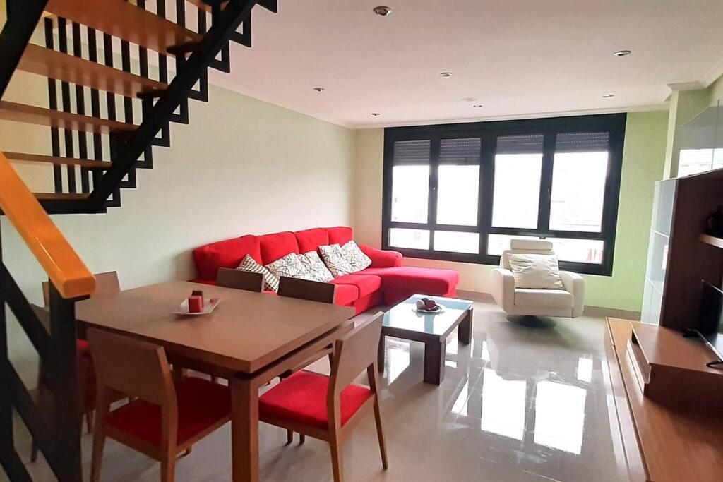 a living room with a red couch and a table at DUPLEX 3 DORMITORIOS PLAYA FOZ in Foz