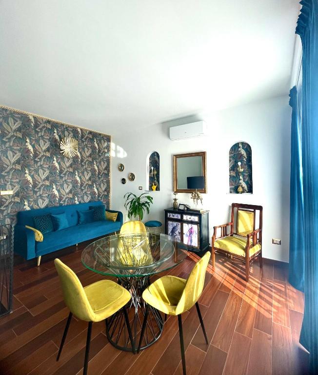 a living room with a glass table and yellow chairs at Charme House Taormina in Taormina
