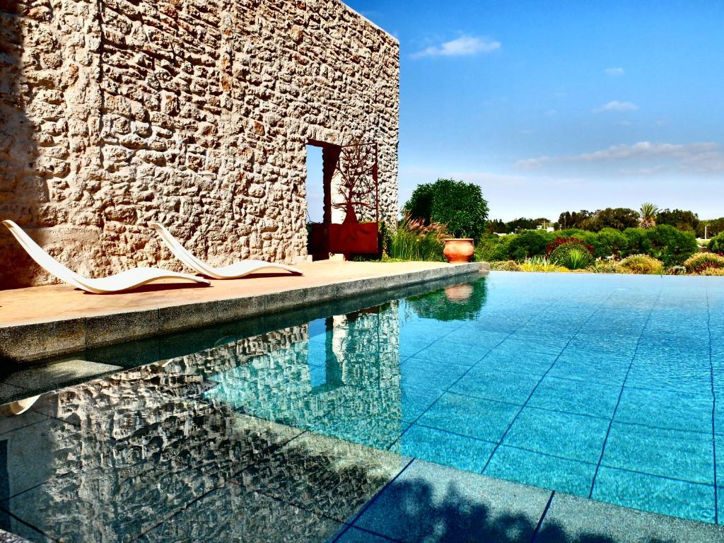 a pool with lounge chairs next to a stone building at Villa Azir in Ghazoua