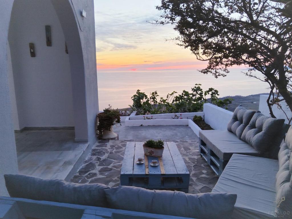 a patio with couches and a table and a sunset at Petalou House in Imerovigli