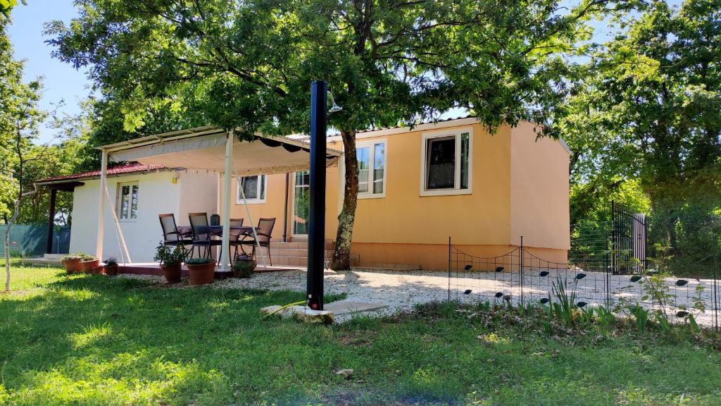 ein kleines gelbes Haus mit einem Tisch im Hof in der Unterkunft Tiny house Dora in Marčana