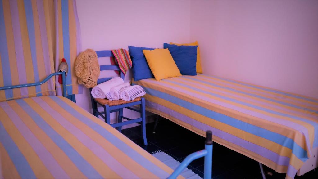 um pequeno quarto com 2 camas e uma cadeira em MareDentro em Mazara del Vallo