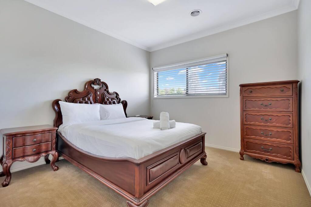 een slaapkamer met een bed, een dressoir en een raam bij Spacious 4BR House In Great Location in Point Cook