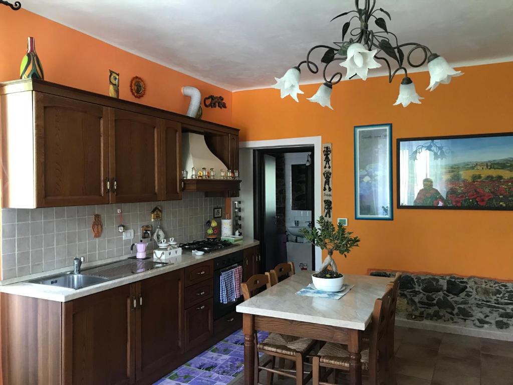 eine Küche mit orangefarbenen Wänden, einem Tisch und einem Waschbecken in der Unterkunft La Casina Di Jessica in Aulla