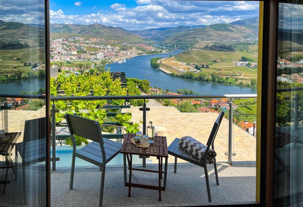 een tafel en stoelen op een balkon met uitzicht op een rivier bij Quinta Pecêga - AL in Peso da Régua