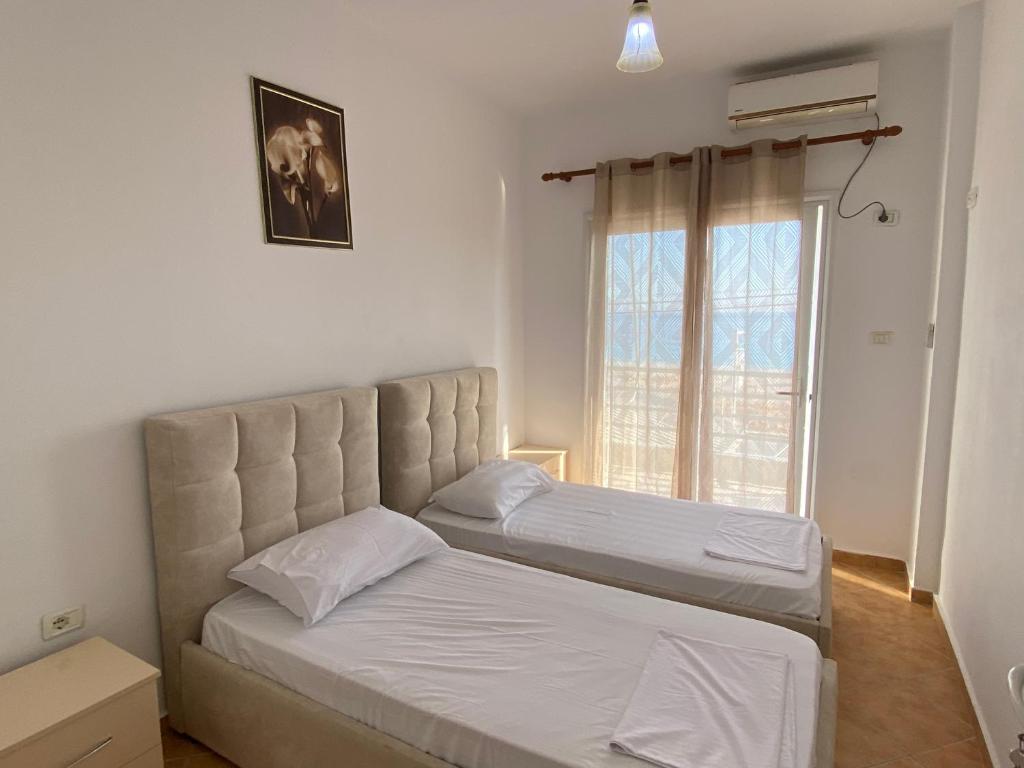 1 dormitorio con 2 camas y ventana en Wave n' Sea Apartments en Himare