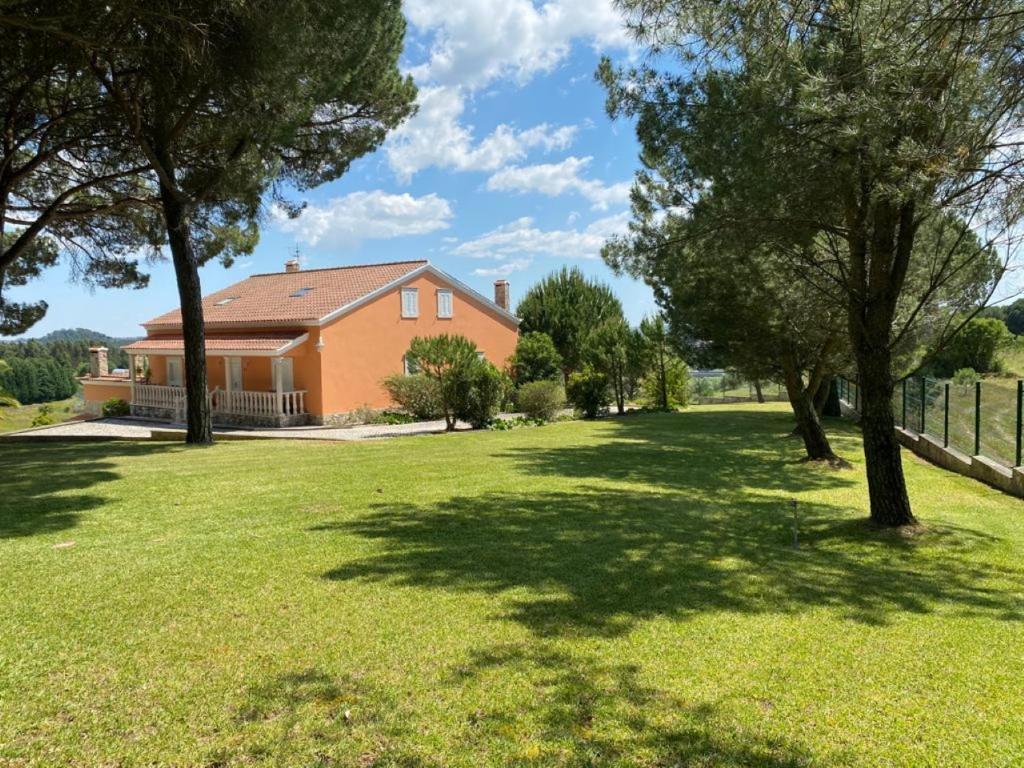 ein Haus in einem Garten mit Bäumen im Gras in der Unterkunft Villa very quiet, fantastic views, ideal for families, fun and relaxation. in São João da Ribeira