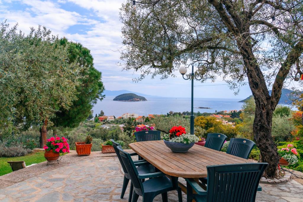 un tavolo e sedie in legno con vista sull'oceano di Villa Elia Kavala - Mediterranean Holiday Villa a PalaiónTsiflíkion