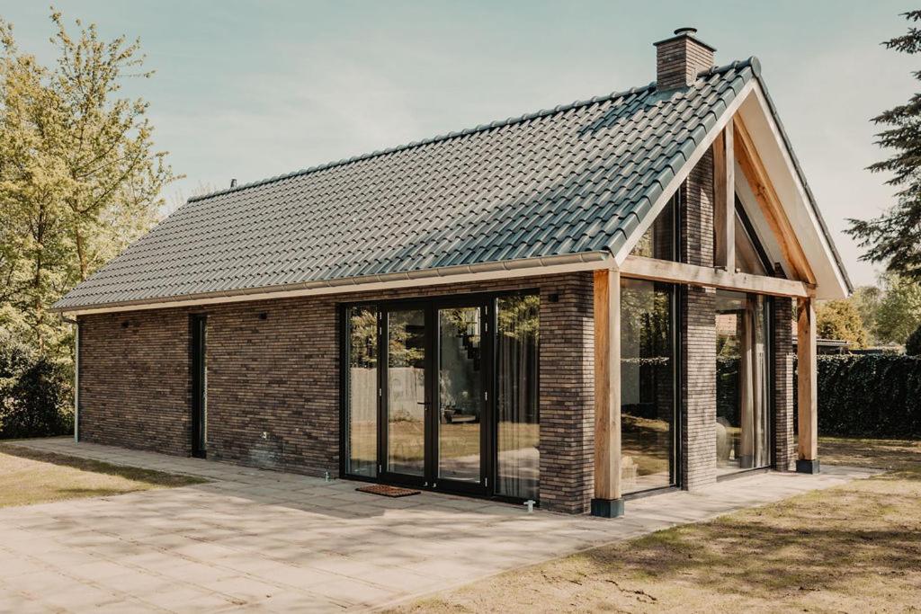 ein Backsteinhaus mit einem Dach mit Glasfenstern in der Unterkunft Luxe schuurwoning 't Nieuwt in Chaam, Nederland in Chaam