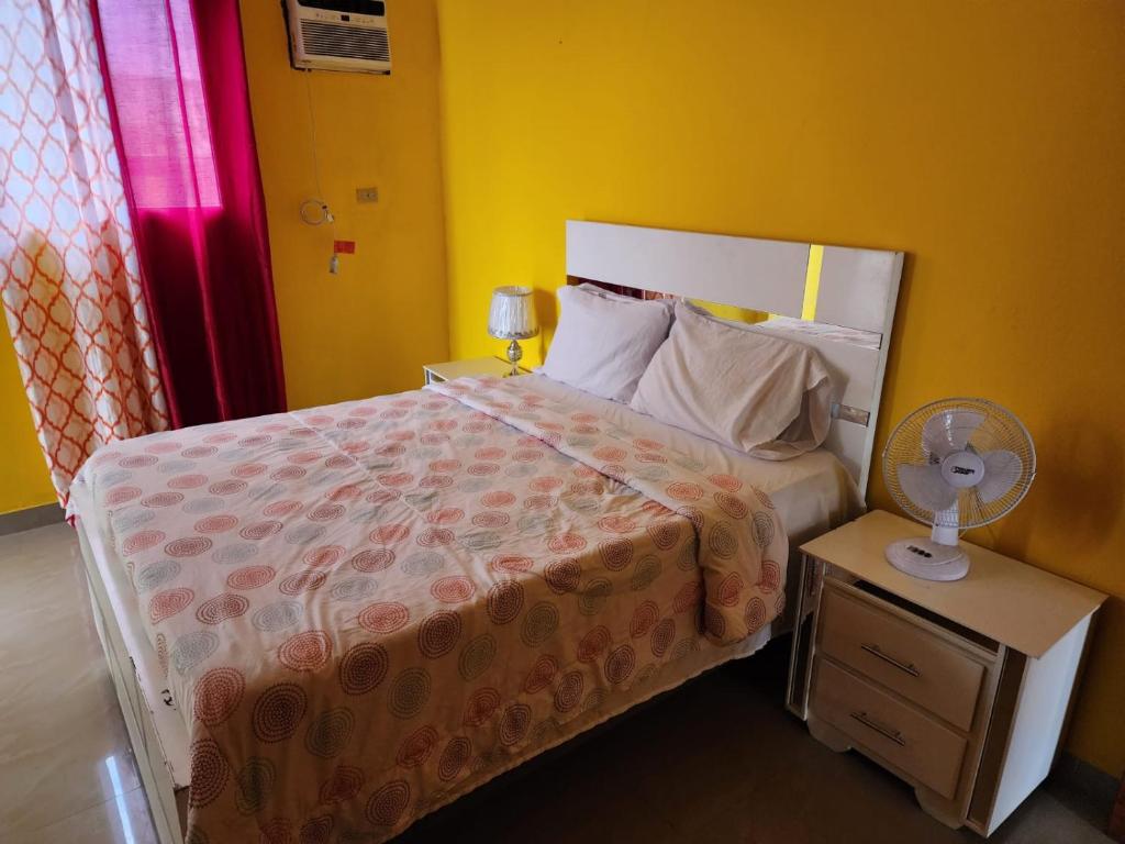 a bedroom with a bed and a night stand with a fan at Super Two Bedroom Penthouse in Peguy-Ville 