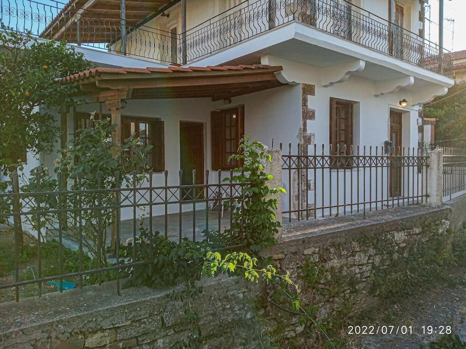 a white house with a balcony and a fence at Archontiko Taxiarches Kymi Evia in Kymi
