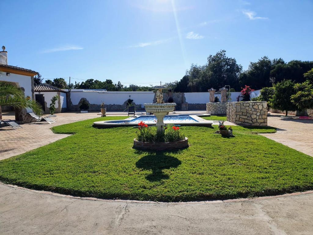 einen Garten mit einem Brunnen inmitten eines Gartens in der Unterkunft El Capricho de Mamá - Chalet con piscina in Barbate