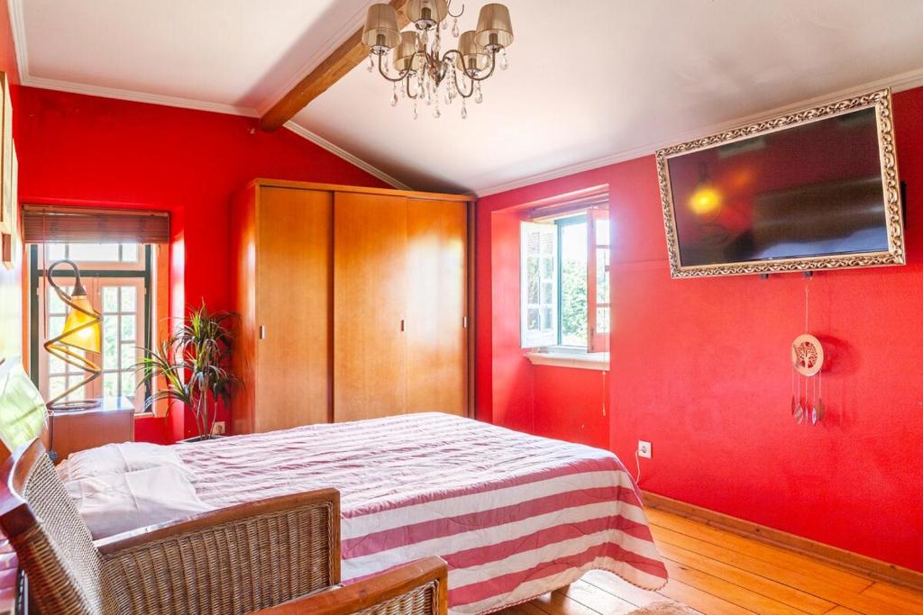 1 dormitorio con paredes rojas, 1 cama y lámpara de araña en B&B Quarto Vermelho Estilo Moderno, 