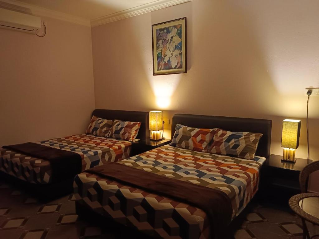 um quarto de hotel com duas camas e um sofá em Alfa Roomstay em Pantai Cenang
