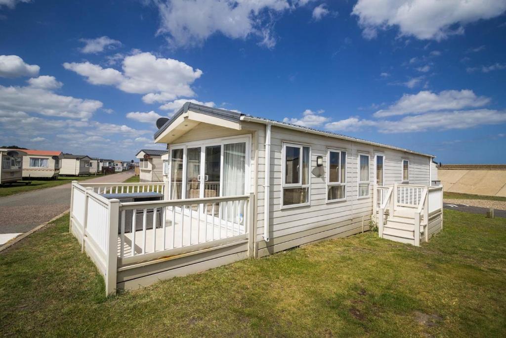a small white house on the side of a yard at Beautiful 6 Berth Caravan By The Beach In Suffolk Ref 40076nd in Lowestoft