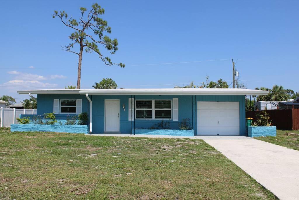 a blue house with a tree and a driveway at Pool house in Port Charlotte in Port Charlotte