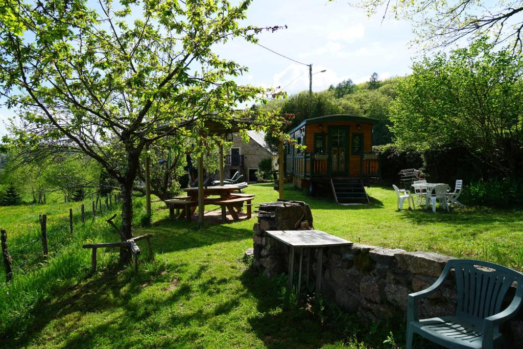 einen Garten mit einem Tisch, einer Bank und einer Hütte in der Unterkunft roulotte maisonthiers in Blanot