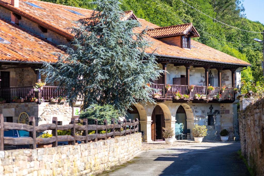 a house with a fence and a tree in front of it at Hotel Spa Casona La Hondonada in Terán