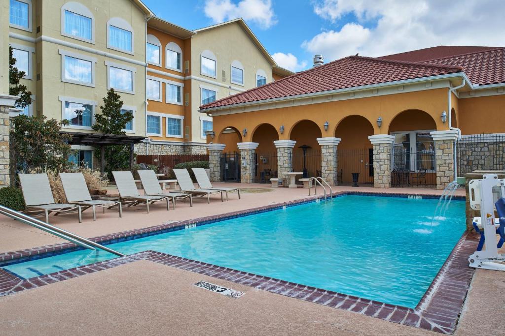 une piscine avec des chaises et un bâtiment dans l'établissement Residence Inn by Marriott Abilene, à Abilene