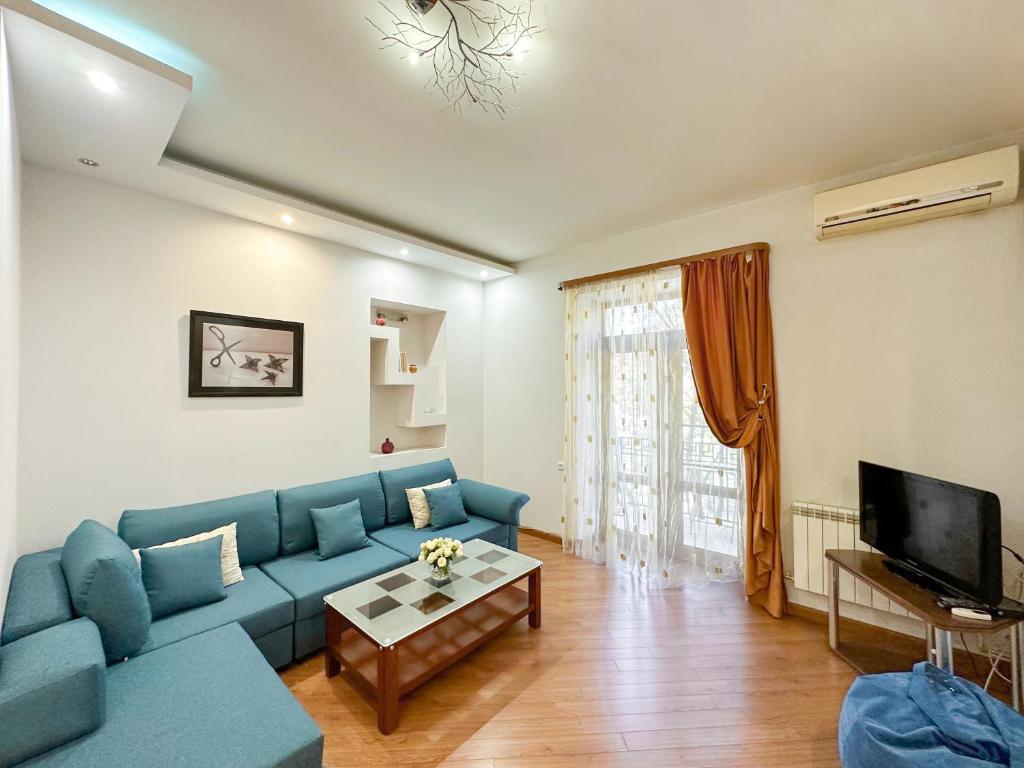 a living room with a blue couch and a tv at RIS Central Apartments Yerevan in Yerevan