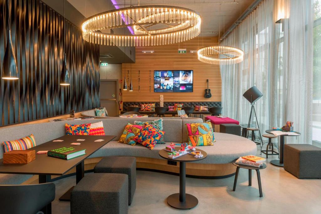 een lobby met een bank, tafels en een tv bij Moxy Ludwigshafen in Ludwigshafen am Rhein