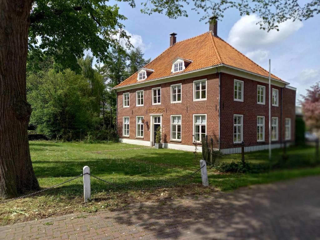 duży dom z czerwonej cegły z drzewem przed nim w obiekcie B&B Huize Placida w mieście Boxmeer