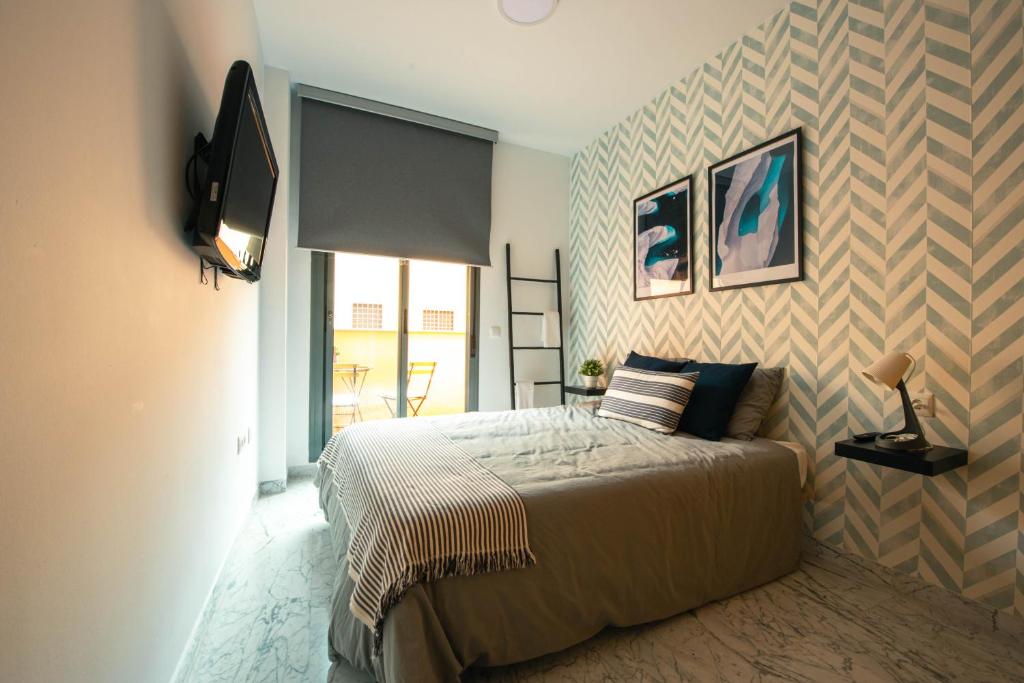 貝萊斯－馬拉加的住宿－Nordik Rooms Village - Chilches "Taby"，一间卧室配有一张床,墙上配有电视