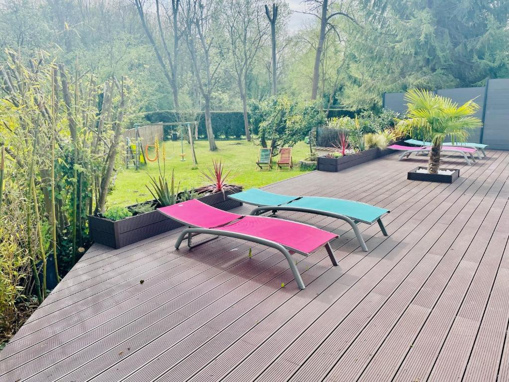 a deck with picnic tables and benches on it at Appartement 120m2 dans maison avec piscine in Boissy-lʼAillerie