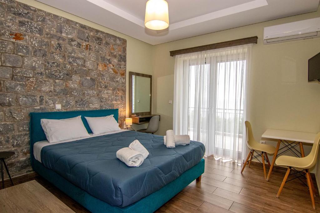 a bedroom with a blue bed and a brick wall at Verga's Apartments in Kalamata