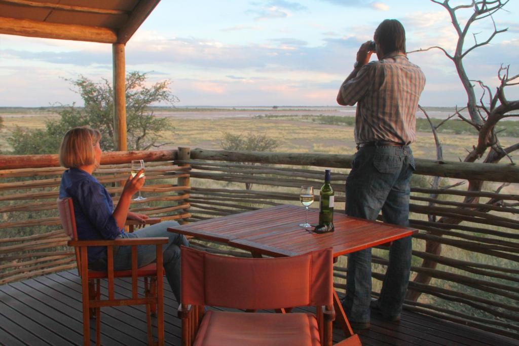 un hombre tomando una foto de una mujer sentada en una mesa en Suricate Tented Kalahari Lodge, en Hoachanas
