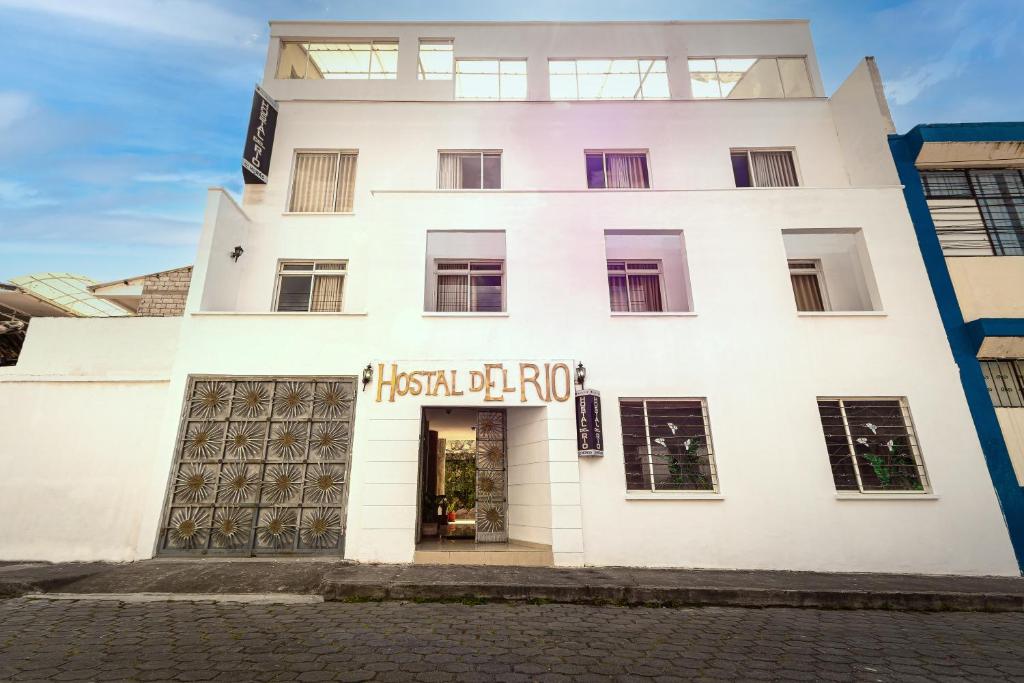 Un edificio bianco con un cartello che dice salsa irlandese di HOSTAL DEL RÍO a Ibarra