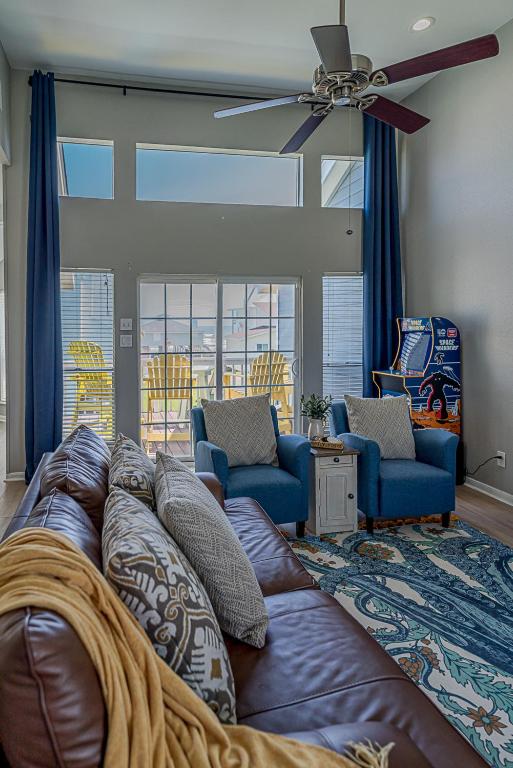 a living room with a brown couch and blue chairs at Hot Tub - Ocean Views - Steps to Private Beach - Quiet Location in Galveston