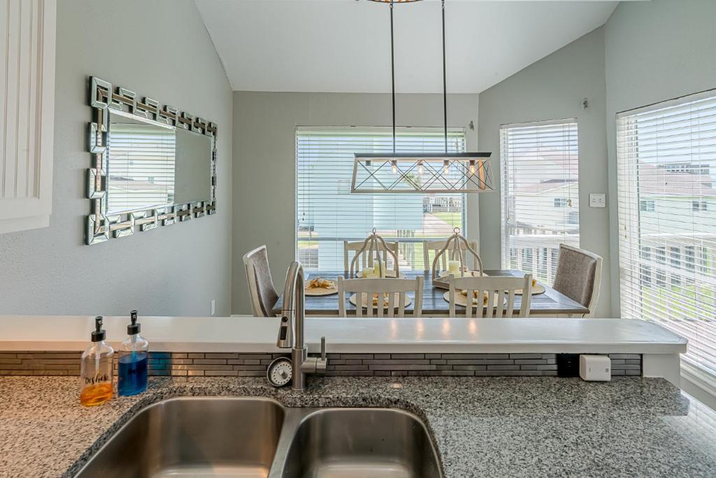 a kitchen with a sink and a table with chairs at Hot Tub - Ocean Views - Steps to Private Beach - Quiet Location in Galveston