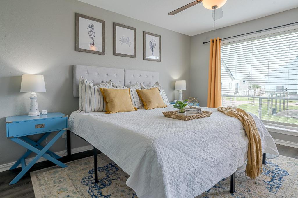 a bedroom with a bed with a blue table and a window at Hot Tub - Ocean Views - Steps to Private Beach - Quiet Location in Galveston
