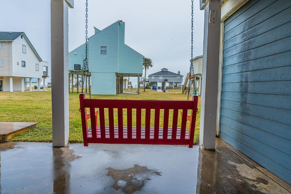 a red bench sitting next to a house at Hot Tub - Ocean Views - Steps to Private Beach - Quiet Location in Galveston