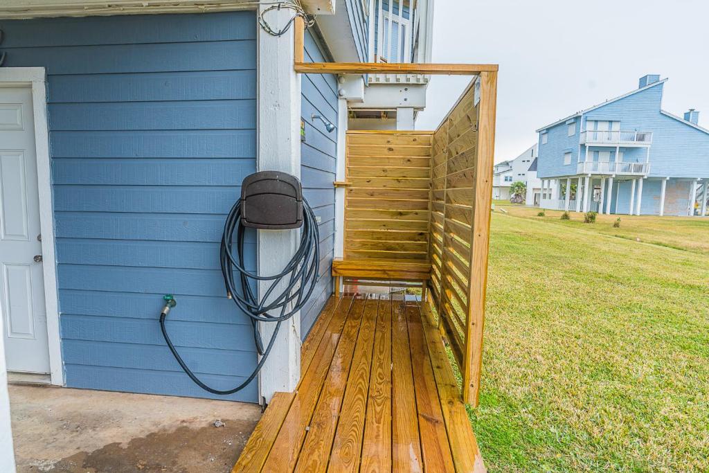 a wooden deck with a hose attached to a house at Hot Tub - Ocean Views - Steps to Private Beach - Quiet Location in Galveston