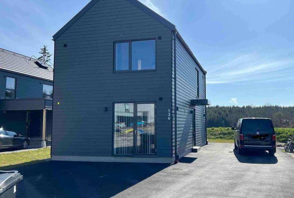 a black house with a van parked in a driveway at Luxurious newly built villa with patio and private parking in Sigtuna