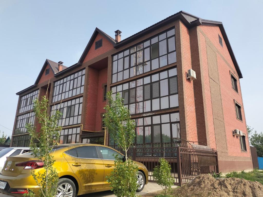 park home uralsk في أورالسك: سيارة صفراء متوقفة أمام مبنى