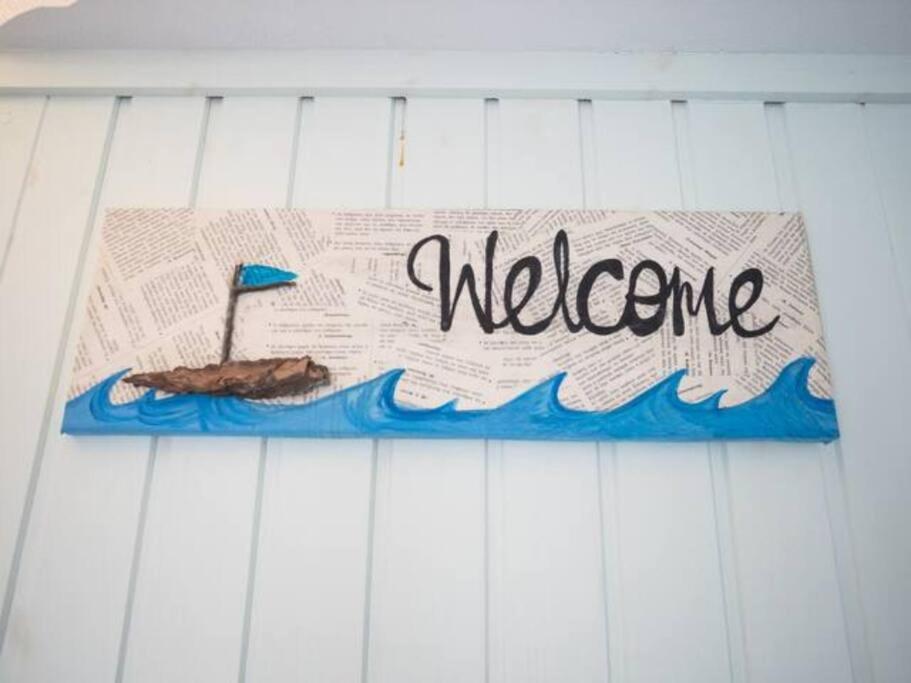a welcome sign with a boat in the water at Amorgos Azur apartment in Tholária