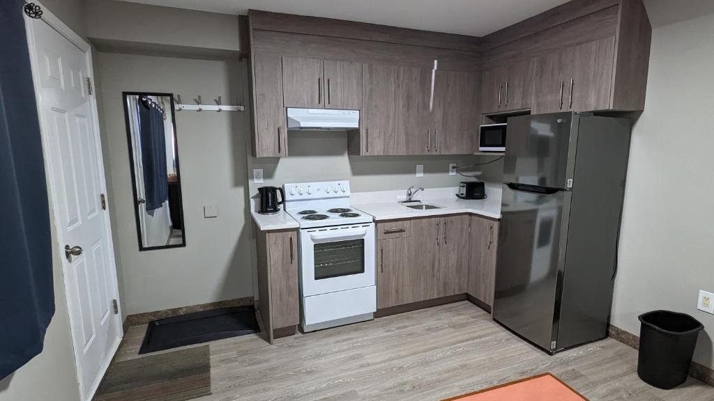 una cocina con electrodomésticos blancos y armarios de madera en Riverside Motel, en Medicine Hat