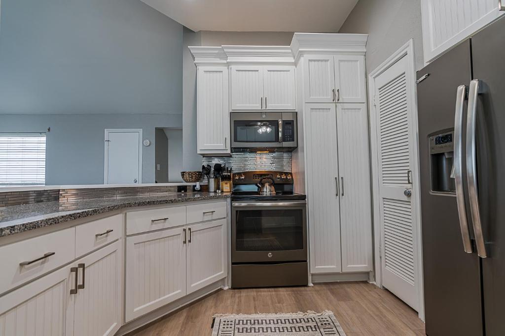 a kitchen with white cabinets and a black refrigerator at Hot Tub - Ocean Views - Steps to Private Beach - Quiet Location in Galveston