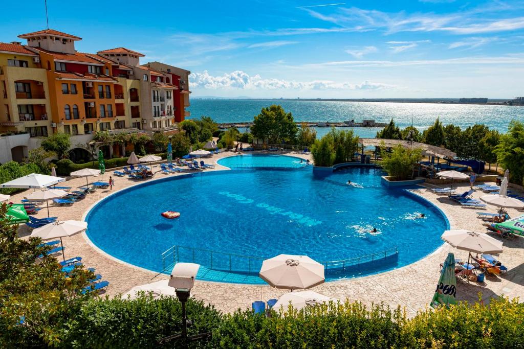 a large swimming pool with chairs and umbrellas at Sea View Apartments - Aheloy in Ravda
