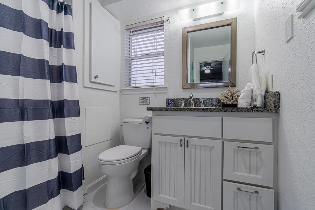 a bathroom with a toilet and a sink and a mirror at Hot Tub - Ocean Views - Steps to Private Beach - Quiet Location in Galveston
