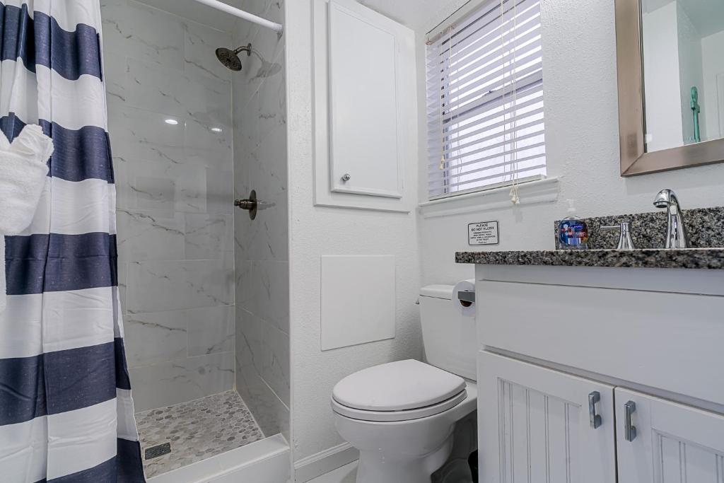 a white bathroom with a toilet and a shower at Hot Tub - Ocean Views - Steps to Private Beach - Quiet Location in Galveston